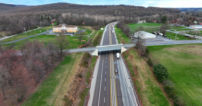 Aerial view of a highway with an overpass surrounding green fields a hotel building and sparse trees in Manheim Pennsylvania United States. Aerial view of a highway with an overpass surrounding green fields a hotel building and sparse trees in Manheim Pennsylvania United States.