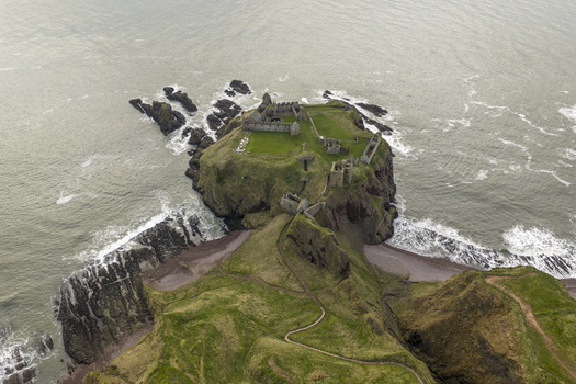 Aerial view of the medieval ruins of Dunnottar Castle on a dramatic cliffside overlooking the North Sea Stonehaven Scotland United Kingdom. Aerial view of the medieval ruins of Dunnottar Castle on a dramatic cliffside overlooking the North Sea Stonehaven Scotland United Kingdom.