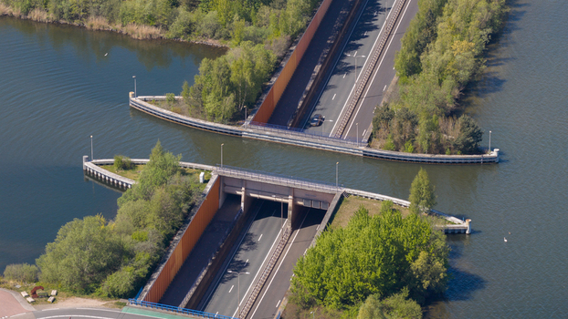 Aerial view of the Aquaduct Veluwemeer with cars driving through the tunnel under the water surface surrounded by lush green trees in Harderwijk Gelderland Netherlands. Aerial view of the Aquaduct Veluwemeer with cars driving through the tunnel under the water surface surrounded by lush green trees in Harderwijk Gelderland Netherlands.