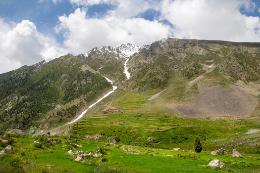 View of Astore Valley with lush green terraced fields and snow capped mountain peaks under a cloudy sky Astore Gilgit Pakistan. View of Astore Valley with lush green terraced fields and snow capped mountain peaks under a cloudy sky Astore Gilgit Pakistan.