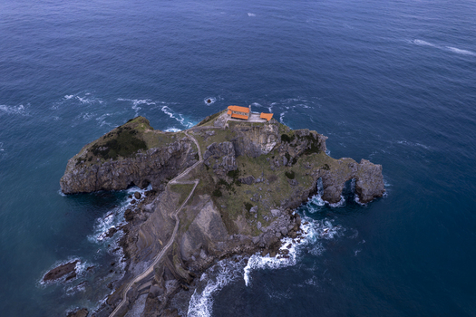 Aerial view of San Juan de Gaztelugatxe a historic hermitage on a rocky islet with a winding stone bridge surrounded by the Bay of Biscay in Gaztelugatxeko Doniene Euskadi Spain.