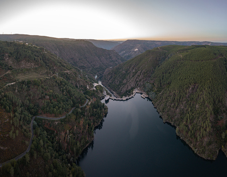Aerial view of Encoro de Santo Estevo dam surrounded by lush green hills winding roads and the Sil River in Ourense Ourense Spain. Aerial view of Encoro de Santo Estevo dam surrounded by lush green hills winding roads and the Sil River in Ourense Ourense Spain.