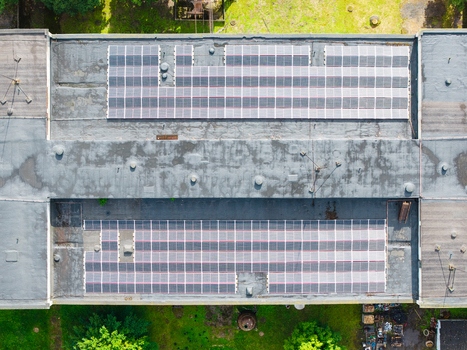 Aerial view of solar panel arrays on a flat industrial building roof with green grass surroundings Olaine Olaine Municipality Latvia. Aerial view of solar panel arrays on a flat industrial building roof with green grass surroundings Olaine Olaine Municipality Latvia.