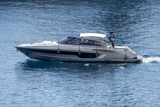 Aerial view of a sleek silver motor yacht cruising through the deep blue waters off the coast of Monaco City Monaco Monaco. Aerial view of a sleek silver motor yacht cruising through the deep blue waters off the coast of Monaco City Monaco Monaco.
