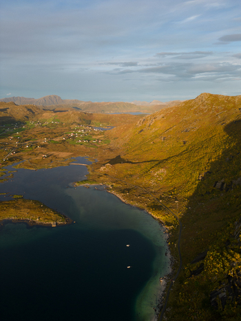 Aerial view of the coastal landscape of Tangstad featuring a calm fjord rugged mountains and scattered houses in the valley Leknes Nordland Norway. Aerial view of the coastal landscape of Tangstad featuring a calm fjord rugged mountains and scattered houses in the valley Leknes Nordland Norway.