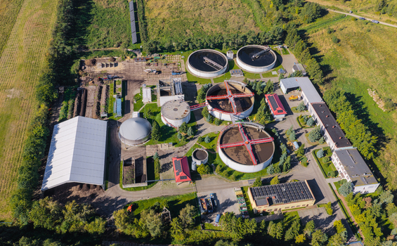 Aerial view of a wastewater treatment plant with circular sedimentation tanks industrial buildings and surrounding green fields in Pomeranian Voivodeship Poland. Aerial view of a wastewater treatment plant with circular sedimentation tanks industrial buildings and surrounding green fields in Pomeranian Voivodeship Poland.