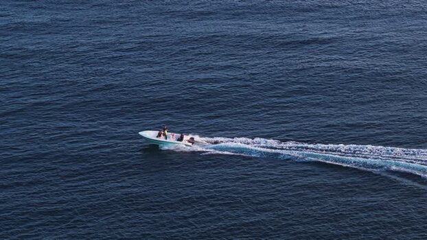 Aerial view of a motorboat with people cruising on the deep blue sea Maldives. Aerial view of a motorboat with people cruising on the deep blue sea Maldives.