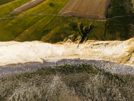 Aerial view of the Beach of the Bois de Cise with its dramatic white chalk cliffs rocky shoreline and adjacent green agricultural fields in Ault Hauts de France France.