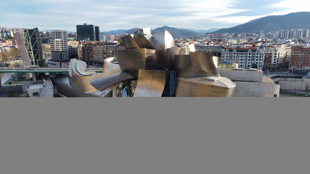 Aerial view of the Guggenheim Museum Bilbao featuring its iconic titanium clad curves surrounded by the urban cityscape and Nervion River in Bilbao Basque Country Spain. Aerial view of the Guggenheim Museum Bilbao featuring its iconic titanium clad curves surrounded by the urban cityscape and Nervion River in Bilbao Basque Country Spain.