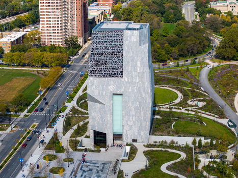 Aerial view of The Obama Presidential Center featuring its stone clad tower with text facade surrounded by landscaped park grounds and nearby city streets in Chicago Illinois United States. Aerial view of The Obama Presidential Center featuring its stone clad tower with text facade surrounded by landscaped park grounds and nearby city streets in Chicago Illinois United States.