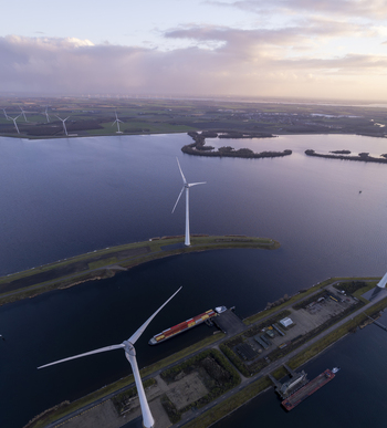 Aerial view of Krammer locks with wind turbines a cargo ship in the waterway and surrounding water and land at sunset in Bruinisse Zeeland Netherlands. Aerial view of Krammer locks with wind turbines a cargo ship in the waterway and surrounding water and land at sunset in Bruinisse Zeeland Netherlands.