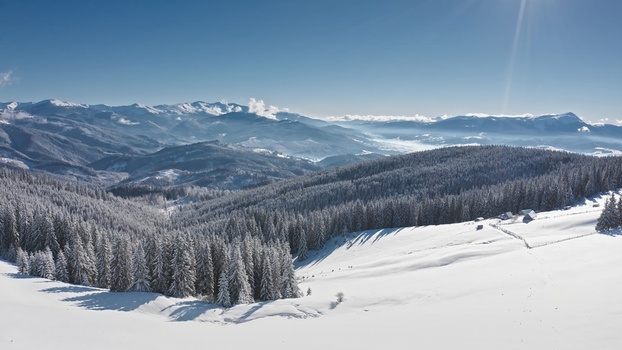 Aerial view of Bukovel ski resort surrounded by snow covered pine forests and majestic Carpathian mountains under a clear blue sky in Bukovel Ivano Frankivsk Oblast Ukraine. Aerial view of Bukovel ski resort surrounded by snow covered pine forests and majestic Carpathian mountains under a clear blue sky in Bukovel Ivano Frankivsk Oblast Ukraine.