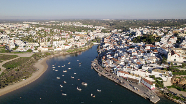 Aerial view of Ferragudo a picturesque fishing village with white washed houses a historic church and small boats floating on the Arade River in Ferragudo Faro District Portugal.