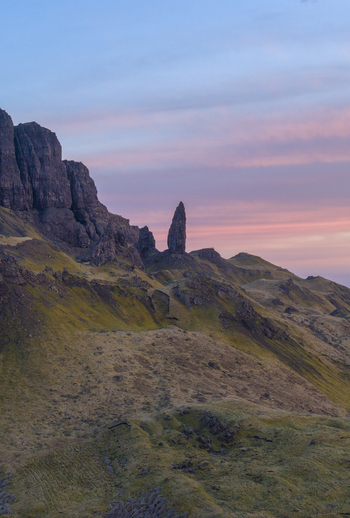 Aerial view of The Storr rock formation with dramatic jagged cliffs and grassy slopes under a soft pink sunset sky Isle of Skye Scotland United Kingdom. Aerial view of The Storr rock formation with dramatic jagged cliffs and grassy slopes under a soft pink sunset sky Isle of Skye Scotland United Kingdom.