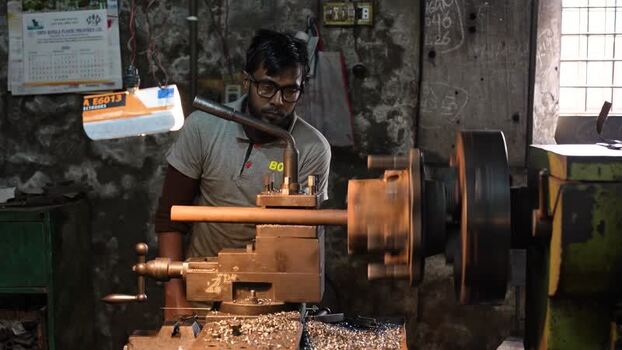 View of a worker operating a lathe machine in a workshop Bangladesh.