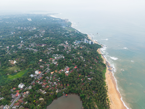 Aerial view of the lush coastal landscape with sandy beaches dense tropical vegetation and residential buildings along the shoreline in Galle Southern Province Sri Lanka. Aerial view of the lush coastal landscape with sandy beaches dense tropical vegetation and residential buildings along the shoreline in Galle Southern Province Sri Lanka.
