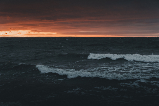 View of the dramatic sunset over the dark rolling waves of the Baltic Sea at Saxby rannik in Saxby Laane maakond Estonia.