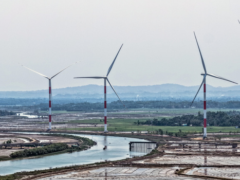 Aerial view of wind turbines standing tall beside the winding river against a backdrop of distant hills Cox s Bazar Chittagong Division Bangladesh. Aerial view of wind turbines standing tall beside the winding river against a backdrop of distant hills Cox s Bazar Chittagong Division Bangladesh.