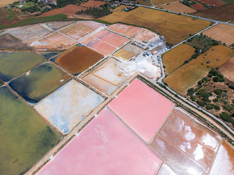 Aerial view of Salines des Trenc salt evaporation ponds with vibrant pink and green water basins under bright daylight in Campos Islas Baleares Spain. Aerial view of Salines des Trenc salt evaporation ponds with vibrant pink and green water basins under bright daylight in Campos Islas Baleares Spain.