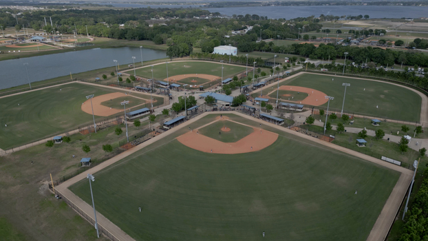 Aerial view of a baseball complex with multiple fields manicured grass dirt infields and surrounding trees near a lake in Polk City Florida United States. Aerial view of a baseball complex with multiple fields manicured grass dirt infields and surrounding trees near a lake in Polk City Florida United States.