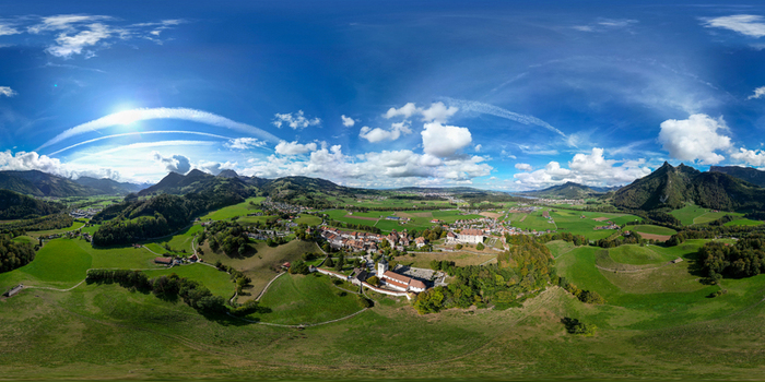 Aerial view of the medieval town of Gruyeres and its historic castle nestled among rolling green hills and the Swiss Alps in Gruyeres Fribourg Switzerland. Aerial view of the medieval town of Gruyeres and its historic castle nestled among rolling green hills and the Swiss Alps in Gruyeres Fribourg Switzerland.