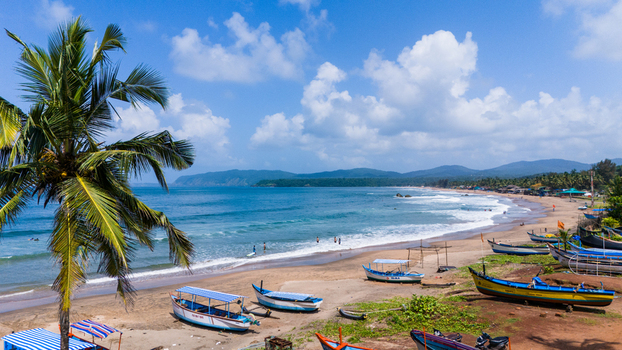 Aerial view of Agonda Beach with colorful fishing boats on the sandy shore a palm tree and turquoise waves under a cloudy sky Agonda Goa India.