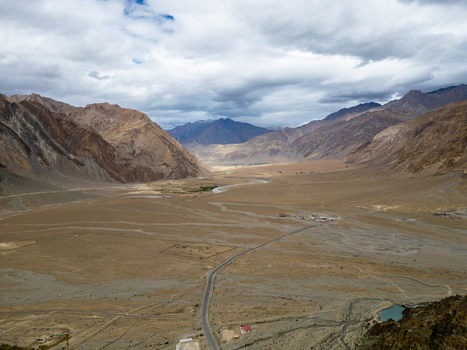 Aerial view of the Zanskar Valley featuring a winding river arid mountain landscape and a road stretching through the vast desert terrain in Zanskar Ladakh India.