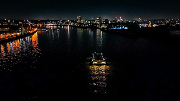 Aerial view of a boat navigating the River Thames at night with the illuminated London skyline and city lights reflecting on the water in London England United Kingdom. Aerial view of a boat navigating the River Thames at night with the illuminated London skyline and city lights reflecting on the water in London England United Kingdom.