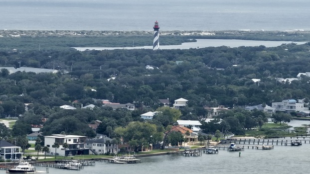 Aerial view of the St. Augustine Lighthouse rising above dense coastal greenery and residential homes along the waterfront in St. Augustine Florida United States. Aerial view of the St. Augustine Lighthouse rising above dense coastal greenery and residential homes along the waterfront in St. Augustine Florida United States.