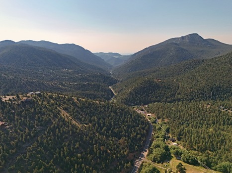 Aerial view of Coal Creek valley featuring dense pine forests winding mountain roads and rugged terrain in Coal Creek Colorado United States. Aerial view of Coal Creek valley featuring dense pine forests winding mountain roads and rugged terrain in Coal Creek Colorado United States.