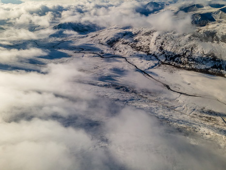 Aerial view of the snow covered Babusar Pass with a winding road through mountain peaks and thick white clouds in Babusar KPK Pakistan.