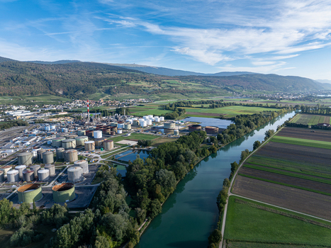 Aerial view of Cressier Refinery with industrial storage tanks situated along the river surrounded by green fields and mountains in Cornaux Neuchatel Switzerland. Aerial view of Cressier Refinery with industrial storage tanks situated along the river surrounded by green fields and mountains in Cornaux Neuchatel Switzerland.