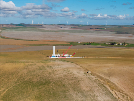 Aerial view of a wind farm construction site with cranes and turbines across rolling hills under a cloudy sky in Swellendam Western Cape South Africa. Aerial view of a wind farm construction site with cranes and turbines across rolling hills under a cloudy sky in Swellendam Western Cape South Africa.