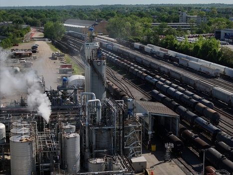 Aerial view of an industrial chemical plant with storage tanks and steam rising next to a large railway yard in Cincinnati OH United States. Aerial view of an industrial chemical plant with storage tanks and steam rising next to a large railway yard in Cincinnati OH United States.