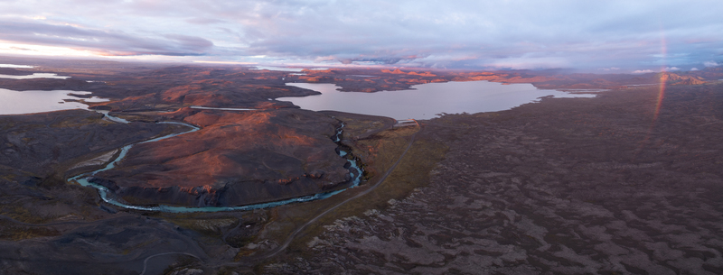 Aerial view of a winding turquoise river carves through dark rugged terrain under a sky painted with soft pastel hues Sigöldugljúfur Rangárþing ytra Iceland. Aerial view of a winding turquoise river carves through dark rugged terrain under a sky painted with soft pastel hues Sigöldugljúfur Rangárþing ytra Iceland.
