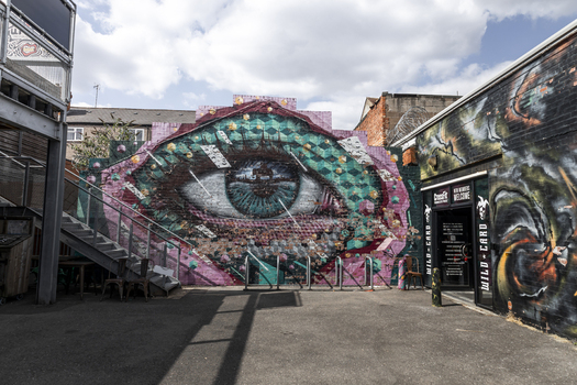 Coventry England United Kingdom 20 July 2026 View of a large colorful eye mural painted on a brick wall in an urban alleyway with geometric patterns.