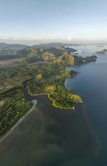 Aerial view of the lush coastline and river estuary near Labuan Bajo with rolling hills and clear blue waters in Komodo East Nusa Tenggara Indonesia. Aerial view of the lush coastline and river estuary near Labuan Bajo with rolling hills and clear blue waters in Komodo East Nusa Tenggara Indonesia.