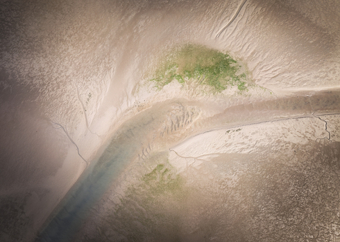 Aerial view of the Rogerstown Estuary showing intricate sand patterns winding water channels and green algae patches in Lusk County Dublin Ireland. Aerial view of the Rogerstown Estuary showing intricate sand patterns winding water channels and green algae patches in Lusk County Dublin Ireland.
