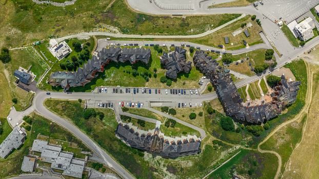 Aerial view of the resort buildings with dark roofs and parking lots surrounded by alpine meadows in Breuil Cervinia Aosta Valley Italy. Aerial view of the resort buildings with dark roofs and parking lots surrounded by alpine meadows in Breuil Cervinia Aosta Valley Italy.