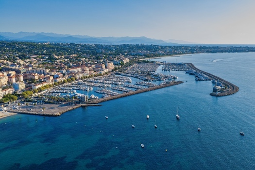Aerial view of the marina with numerous yachts and boats docked surrounded by the historic town and coastline of the French Riviera in Antibes Provence Alpes Cote d Azur France. Aerial view of the marina with numerous yachts and boats docked surrounded by the historic town and coastline of the French Riviera in Antibes Provence Alpes Cote d Azur France.