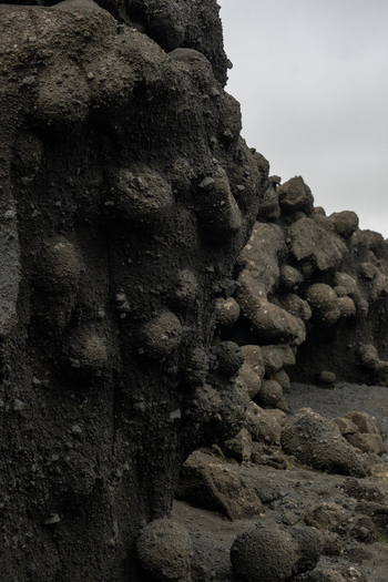View of dark porous lava rock formations rise from the barren landscape under an overcast sky contrasting textures in Skaftárhreppur Skaftárhreppur Iceland. View of dark porous lava rock formations rise from the barren landscape under an overcast sky contrasting textures in Skaftárhreppur Skaftárhreppur Iceland.