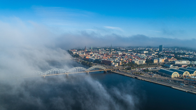 Aerial view of the Daugava River the iconic Railway Bridge and the historic skyline of Riga partially obscured by low hanging morning fog in Riga Latvia. Aerial view of the Daugava River the iconic Railway Bridge and the historic skyline of Riga partially obscured by low hanging morning fog in Riga Latvia.
