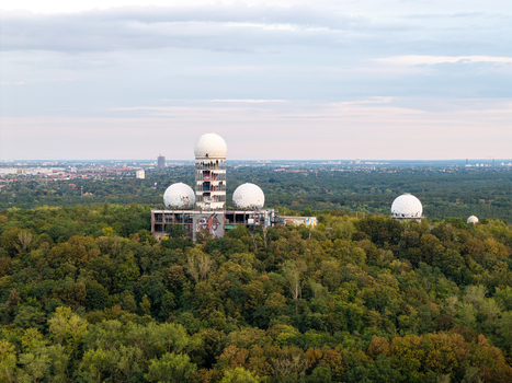 Aerial view of the abandoned Teufelsberg NSA Station with its iconic white radomes and graffiti covered structures rising above the surrounding forest in Berlin Berlin Germany.