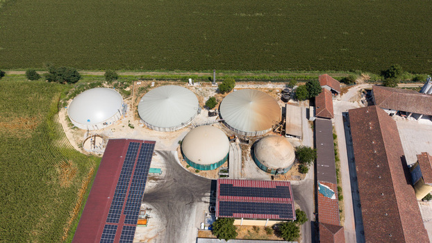 Aerial view of a biomethane production facility with storage tanks solar panels on rooftops and agricultural buildings surrounded by fields in Tavazzano con Villavesco Lombardy Italy.