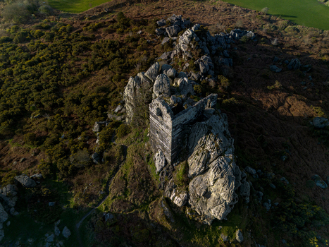 Aerial view of the historic stone chapel atop the rocky outcrop of Roche Rock surrounded by rugged moorland in Roche Cornwall United Kingdom. Aerial view of the historic stone chapel atop the rocky outcrop of Roche Rock surrounded by rugged moorland in Roche Cornwall United Kingdom.