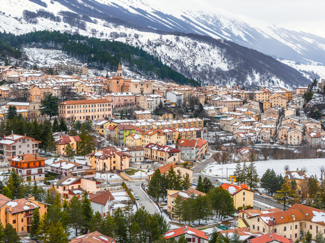 Aerial view of Pescocostanzo village nestled in the snow covered mountains of the Apennines with historic stone buildings terracotta rooftops and pine trees in Pescocostanzo Abruzzo Italy.
