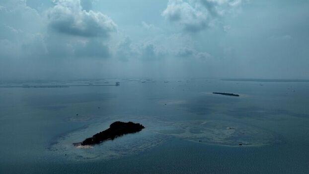 Aerial view of Pulau Lima Resort surrounded by calm blue waters and scattered small islands under a cloudy sky in Kasemen Banten Indonesia. Aerial view of Pulau Lima Resort surrounded by calm blue waters and scattered small islands under a cloudy sky in Kasemen Banten Indonesia.
