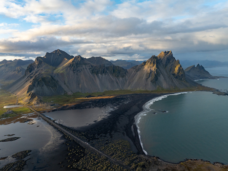 Aerial view of the stark black sand beach meeting the restless sea beneath the watchful gaze of jagged mountains Höfn Iceland. Aerial view of the stark black sand beach meeting the restless sea beneath the watchful gaze of jagged mountains Höfn Iceland.