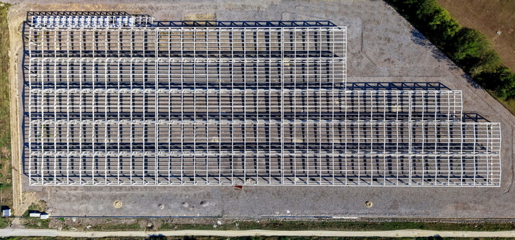 Aerial view of a large industrial hall structure under construction with a metal framework casting long shadows on the gravel ground in Kovin Vojvodina Serbia. Aerial view of a large industrial hall structure under construction with a metal framework casting long shadows on the gravel ground in Kovin Vojvodina Serbia.