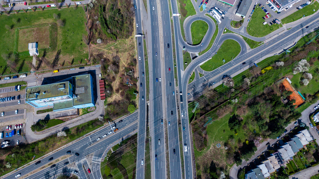 Aerial view of a bustling highway cutting through vibrant green spaces adjacent to structured buildings and circular roads Chodov Prague Czechia. Aerial view of a bustling highway cutting through vibrant green spaces adjacent to structured buildings and circular roads Chodov Prague Czechia.